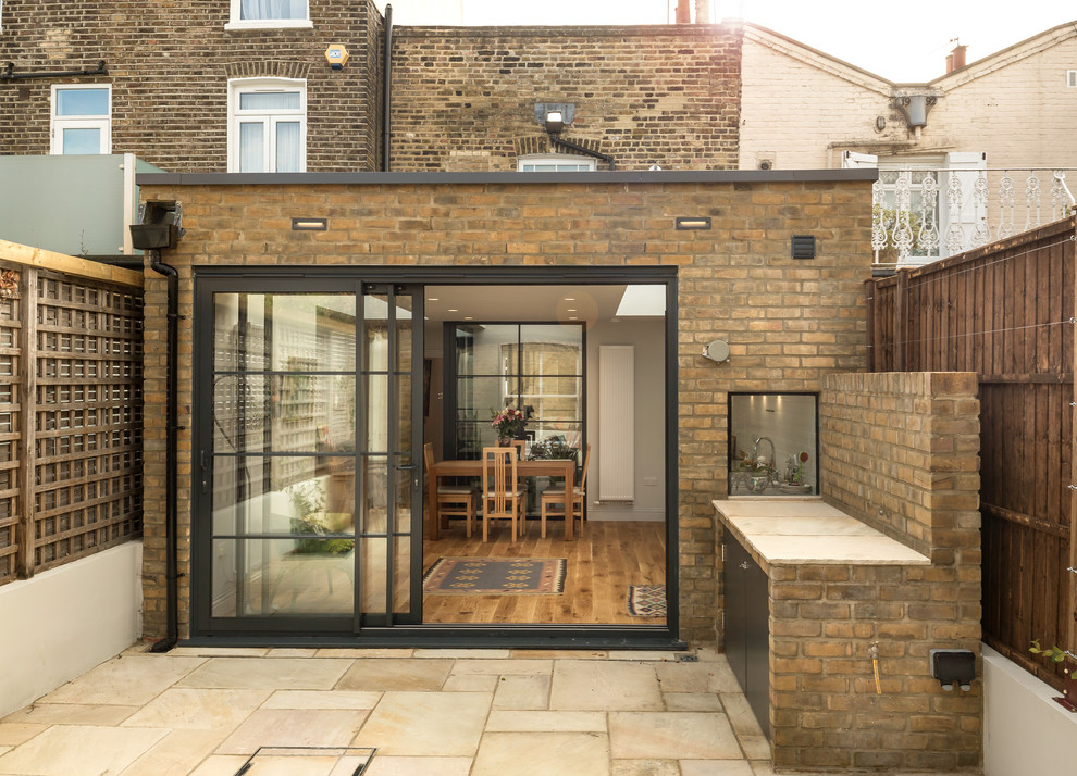 Inspiration for a small contemporary back patio in London with an outdoor kitchen and natural stone paving.