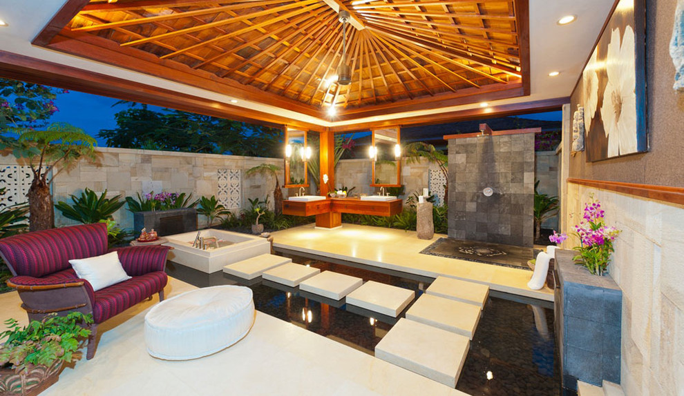 Large tropical backyard patio in Hawaii with an outdoor shower and a roof extension.