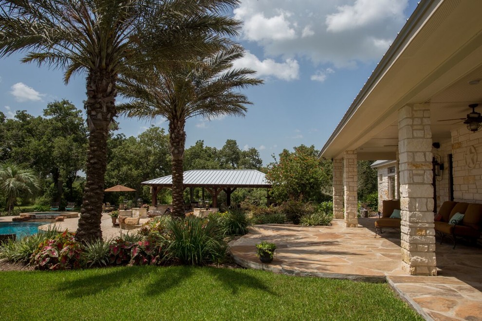 Großer Patio hinter dem Haus mit Outdoor-Küche, Natursteinplatten und Gazebo in Houston