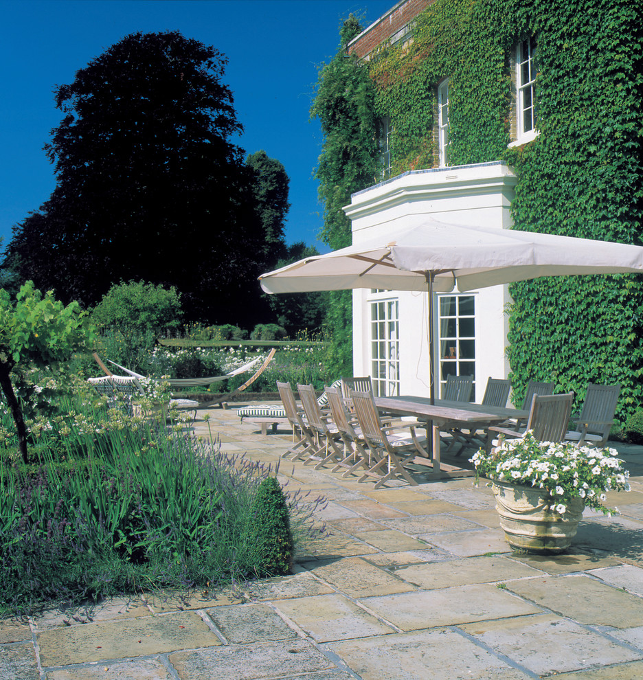 Exemple d'une grande terrasse chic avec des pavés en pierre naturelle.