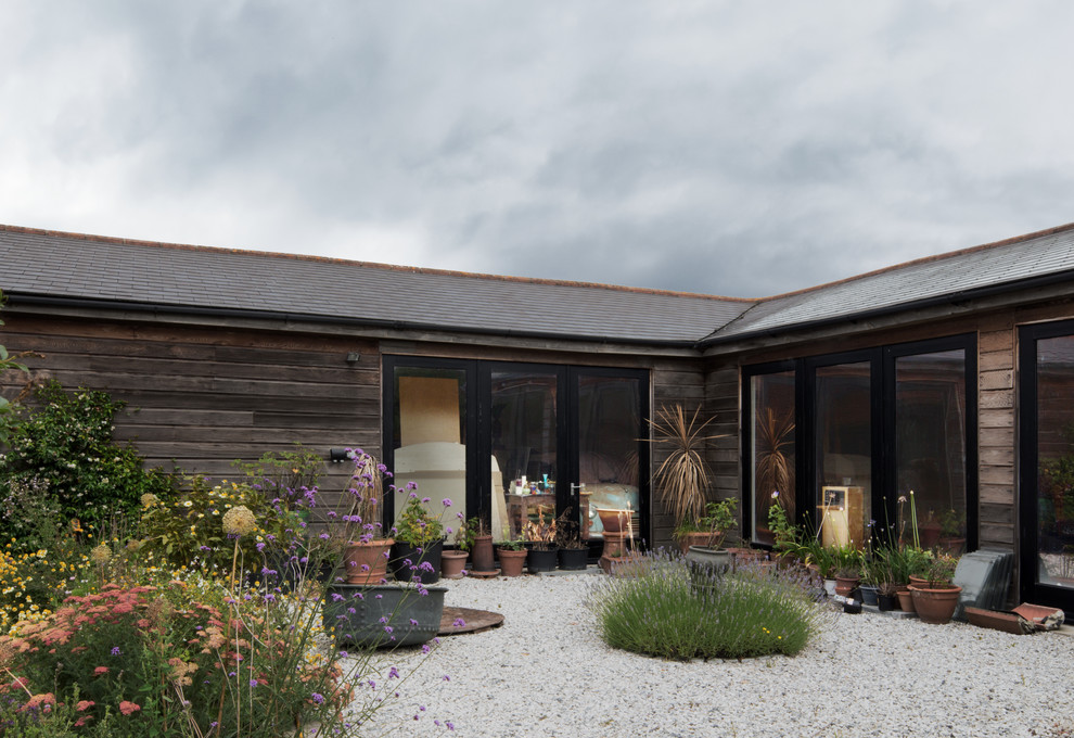 Photo of a large scandi courtyard patio in Hampshire with a potted garden, gravel and no cover.