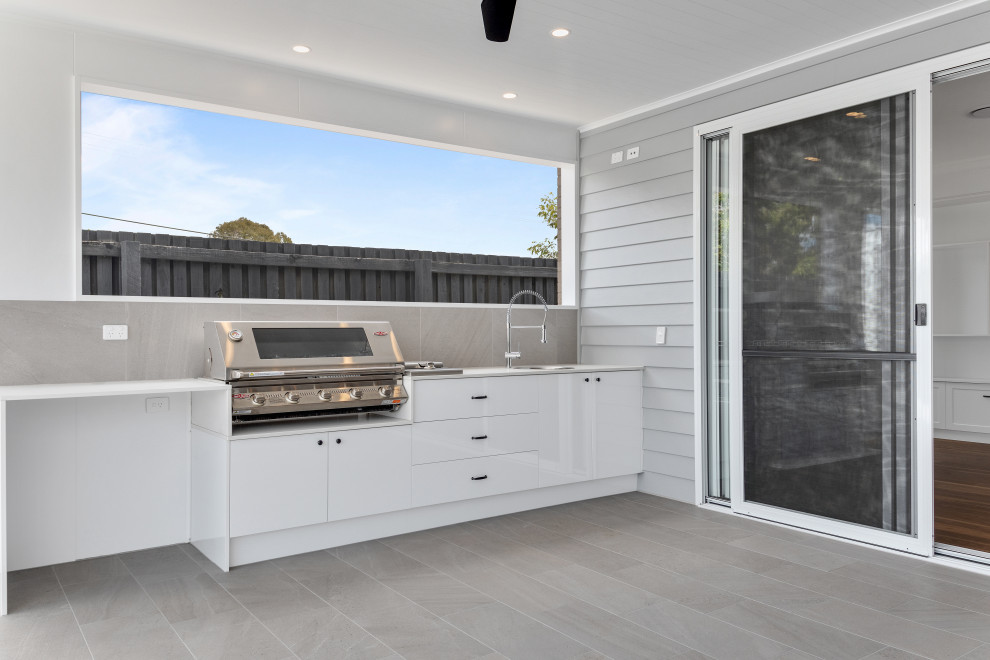 Idée de décoration pour une terrasse arrière de taille moyenne avec une cuisine d'été, du carrelage et une extension de toiture.
