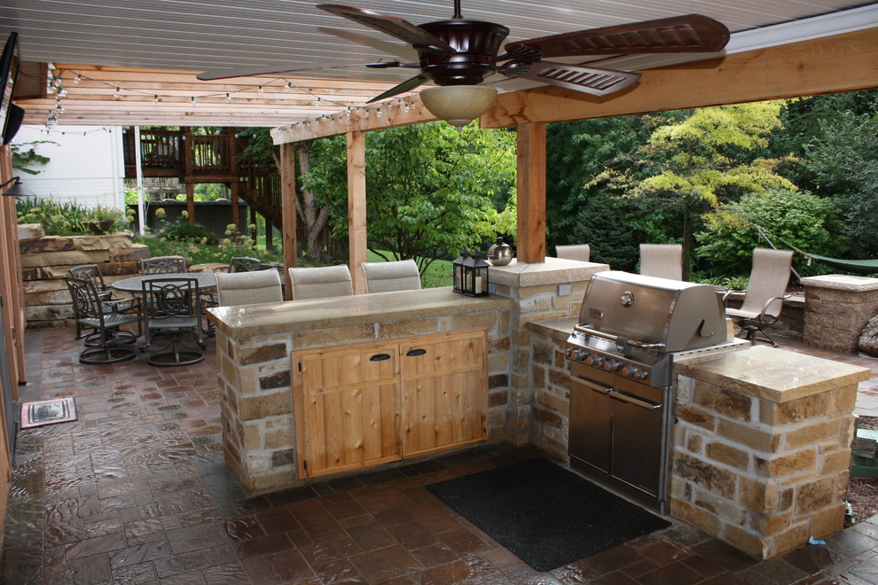 Mid-sized elegant backyard stone patio kitchen photo in Omaha with a pergola
