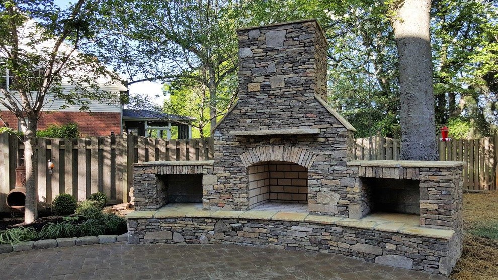Exemple d'une terrasse arrière craftsman de taille moyenne avec un foyer extérieur, des pavés en pierre naturelle et aucune couverture.