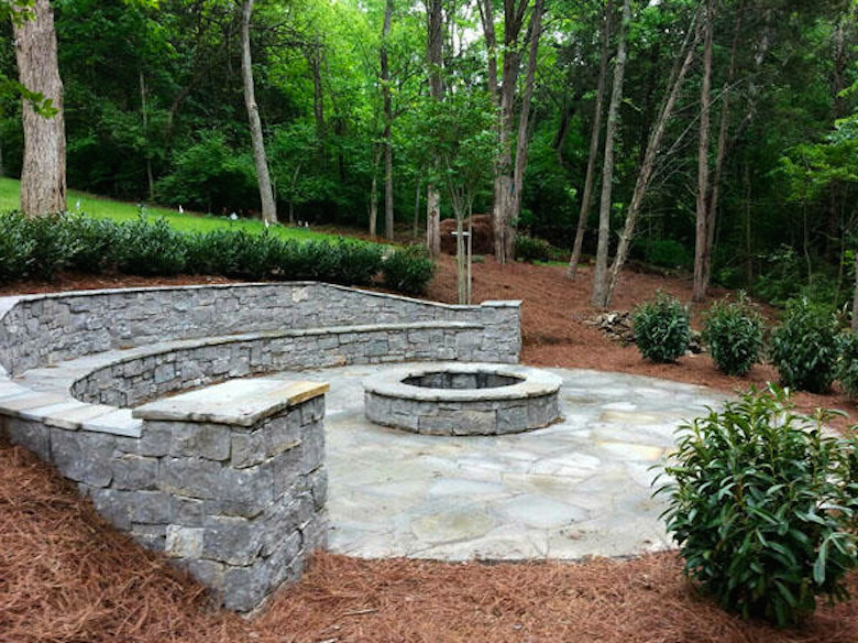 This is an example of a medium sized rustic back patio in Nashville with natural stone paving, a fire feature and no cover.