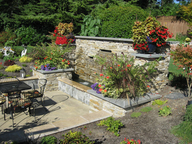 Diseño de patio tradicional grande sin cubierta en patio trasero con fuente y adoquines de hormigón