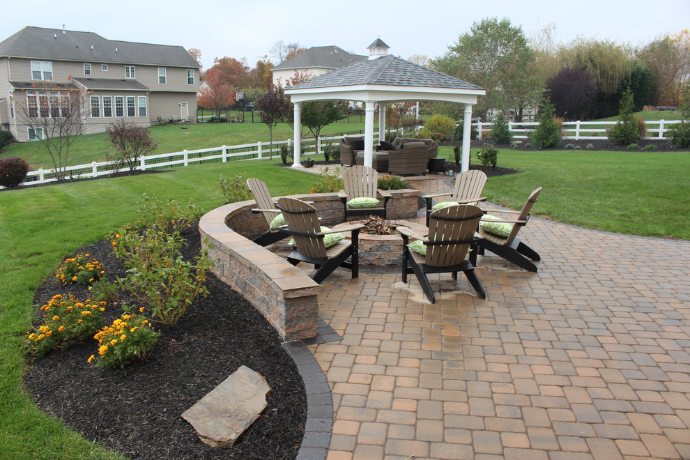 Example of a mid-sized classic backyard brick patio design in Other with a fire pit and no cover