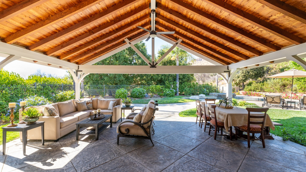 Expansive classic back patio in Los Angeles with an outdoor kitchen, brick paving and a roof extension.