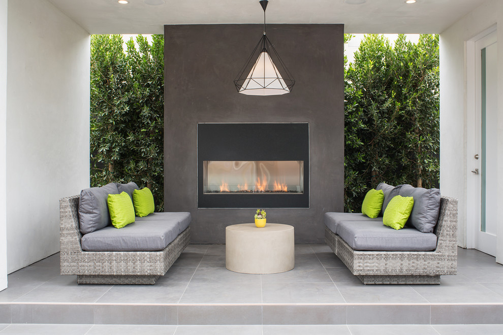 This is an example of a medium sized contemporary back patio in Los Angeles with tiled flooring, a roof extension and a fireplace.