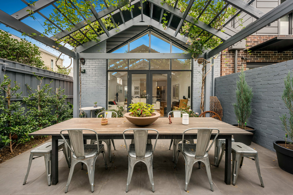 Diseño de patio de estilo de casa de campo en patio trasero con losas de hormigón y pérgola