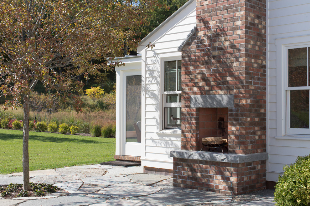 Idee per un patio o portico country dietro casa con un focolare, pavimentazioni in pietra naturale e nessuna copertura