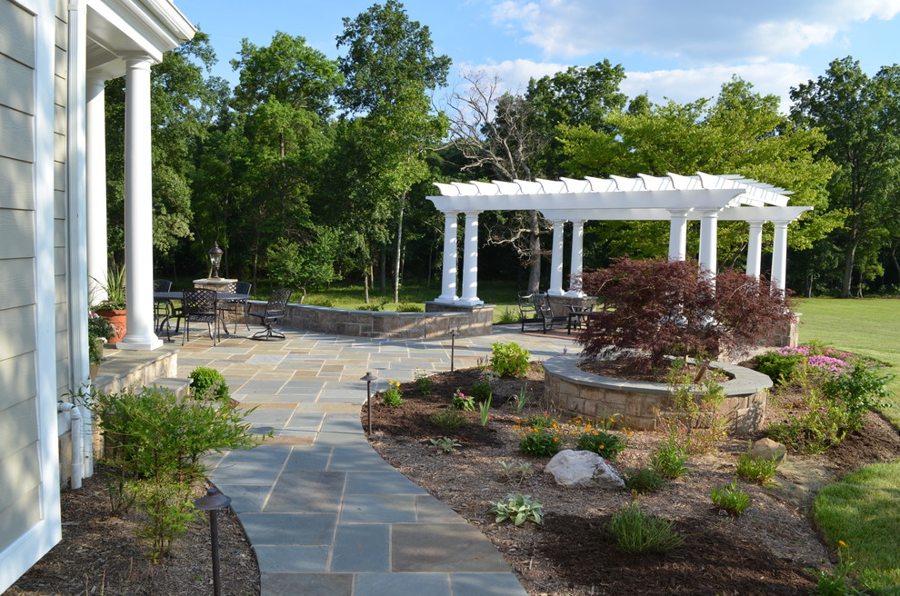 Immagine di un grande patio o portico chic dietro casa con pavimentazioni in pietra naturale e una pergola