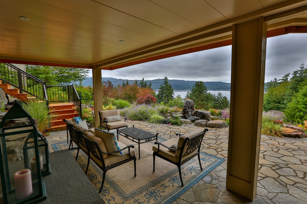 Design ideas for a large modern back patio in Seattle with a water feature, natural stone paving and no cover.