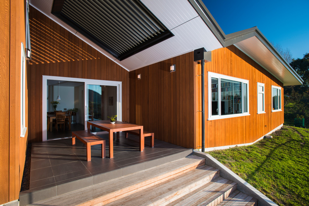 Идея дизайна: двор среднего размера на заднем дворе в стиле модернизм с покрытием из плитки и навесом