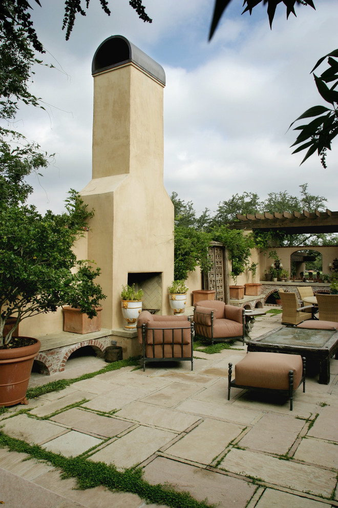 Esempio di un patio o portico classico con un focolare e una pergola