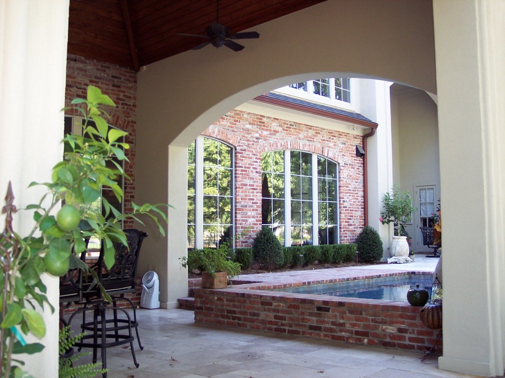 Inspiration for a large mediterranean backyard brick patio kitchen remodel in New Orleans with a roof extension