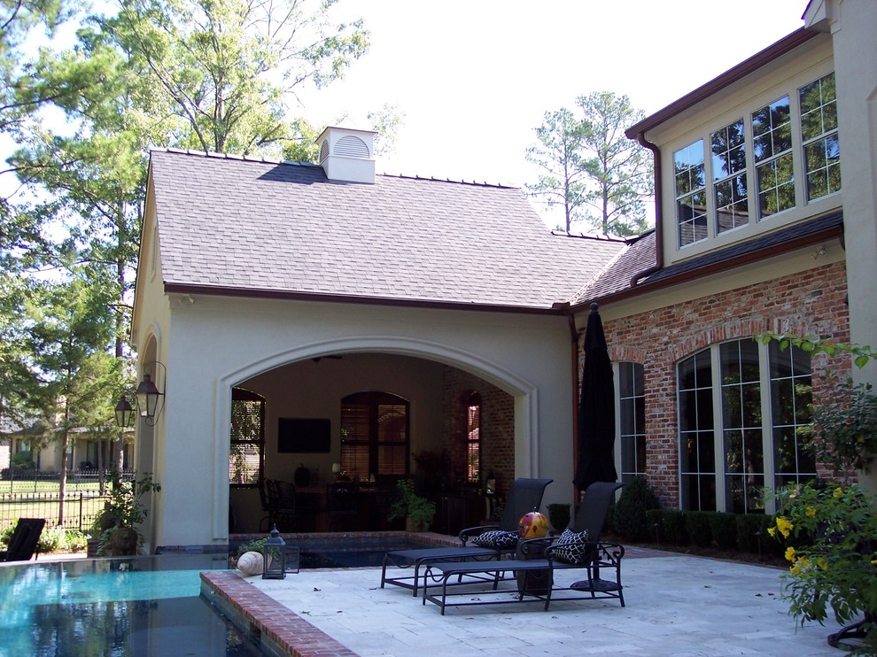 This is an example of a large mediterranean back patio in New Orleans with an outdoor kitchen, brick paving and a roof extension.