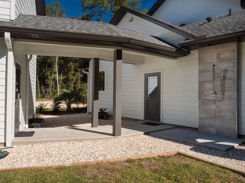 Esempio di un patio o portico chic di medie dimensioni e davanti casa con lastre di cemento e un tetto a sbalzo