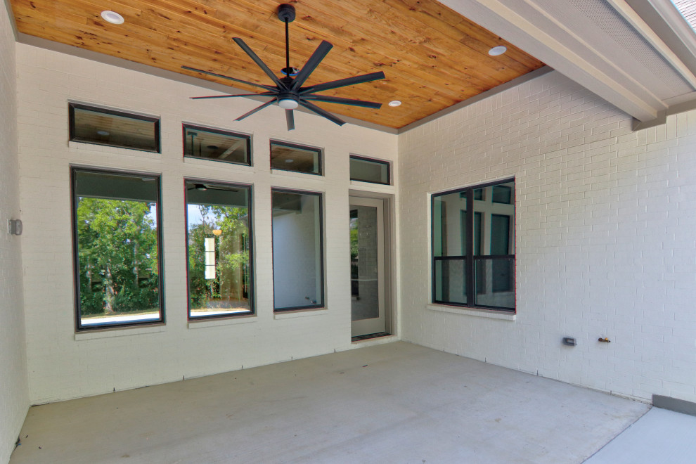 Immagine di un patio o portico chic di medie dimensioni e dietro casa con un tetto a sbalzo e lastre di cemento