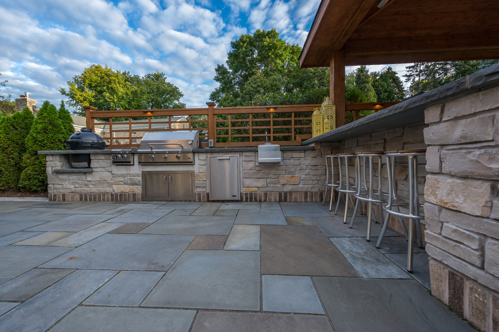Ejemplo de patio tradicional grande en patio trasero con cocina exterior, cenador y adoquines de piedra natural