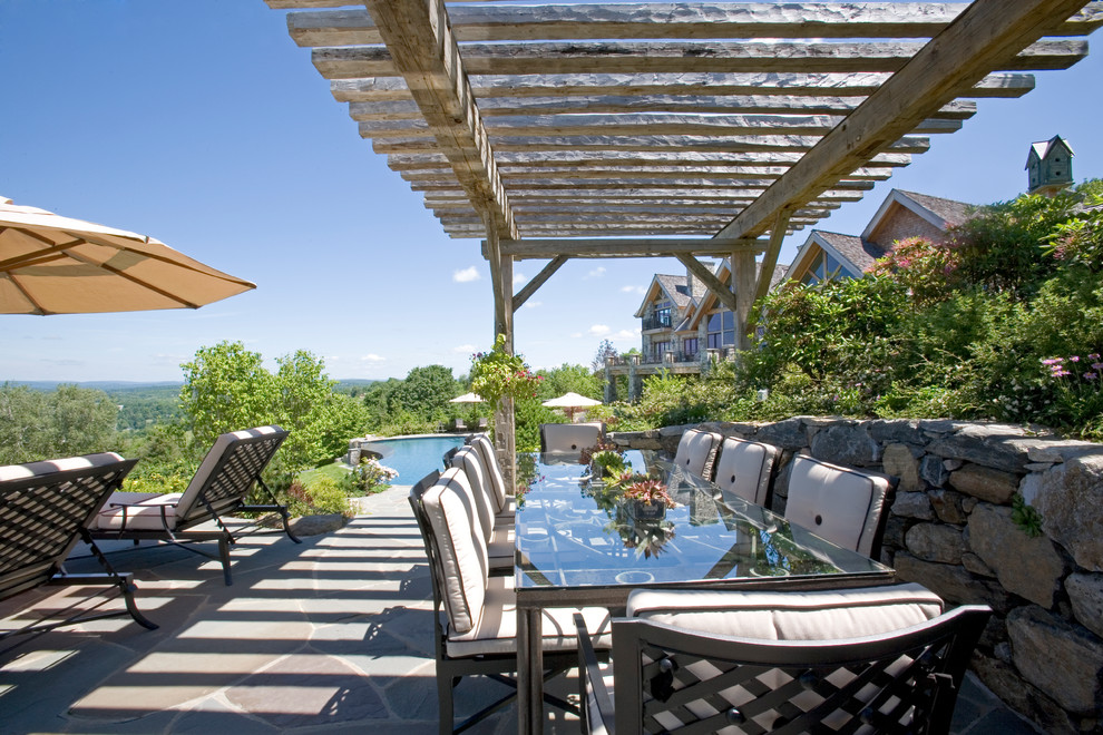 Example of a large mountain style backyard stone patio design in New York with a pergola