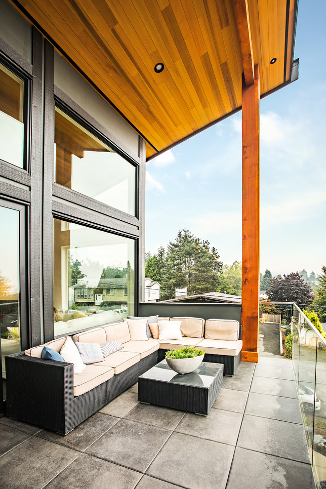 This is an example of a medium sized contemporary front patio in Vancouver with concrete paving and a roof extension.