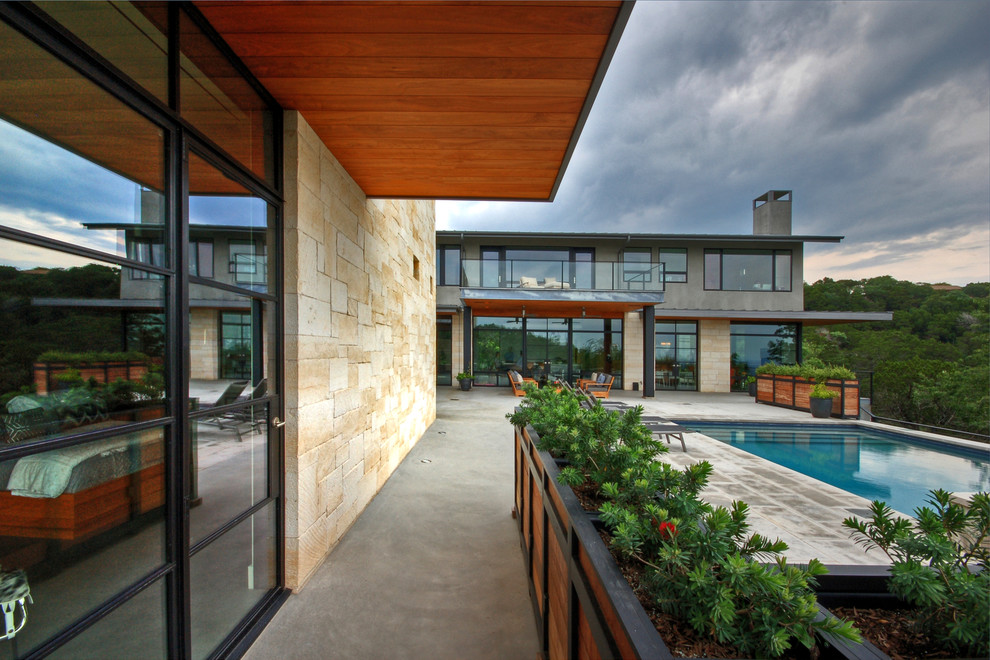 Cette image montre une terrasse design avec une extension de toiture.