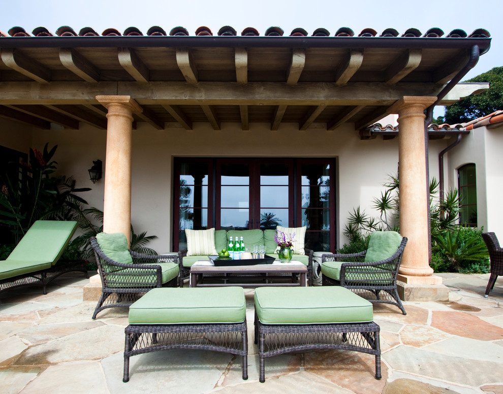 Cette photo montre une terrasse chic avec des pavés en pierre naturelle et une extension de toiture.