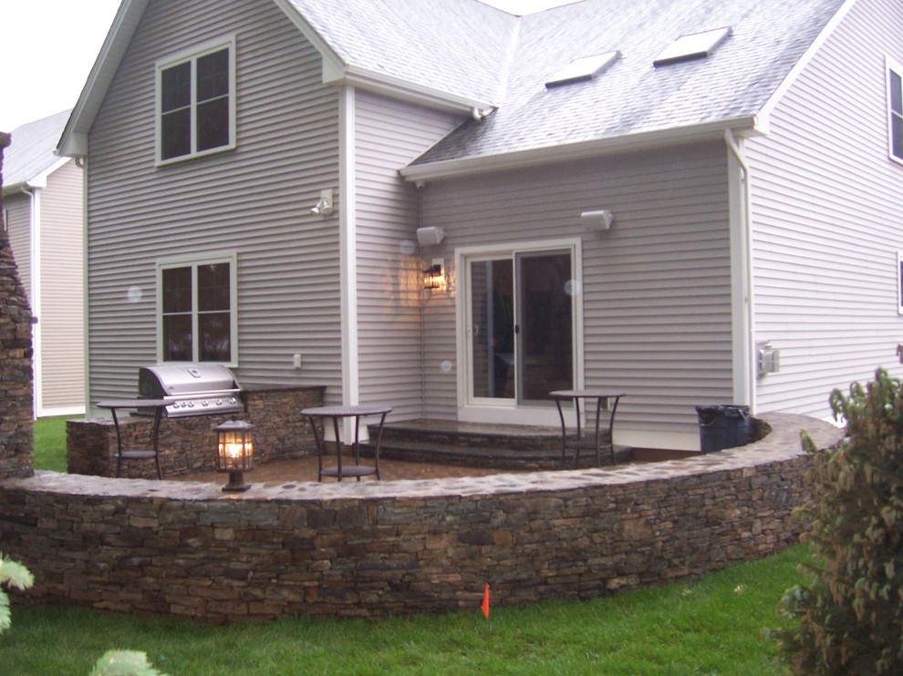 Esempio di un patio o portico american style di medie dimensioni e dietro casa con pavimentazioni in pietra naturale e nessuna copertura