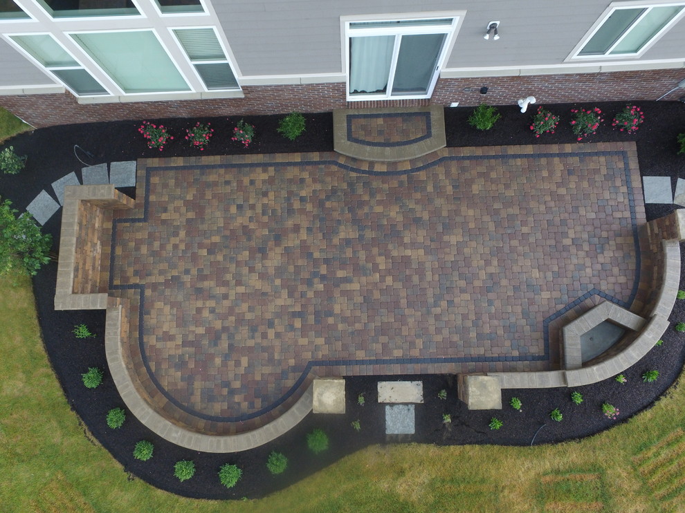 Cette photo montre une terrasse arrière tendance avec un foyer extérieur, des pavés en béton et aucune couverture.