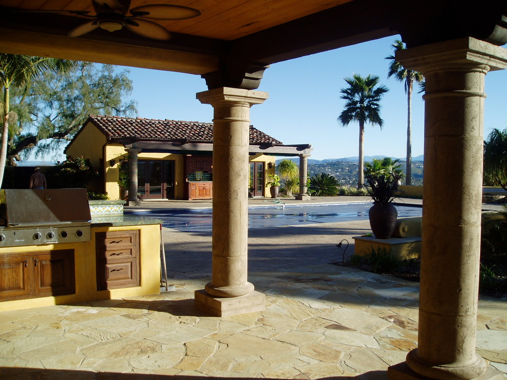 Imagen de patio mediterráneo grande con cocina exterior y adoquines de piedra natural