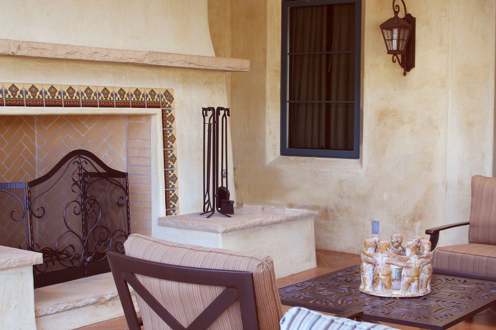 Esempio di un grande patio o portico mediterraneo dietro casa con un focolare, piastrelle e un parasole