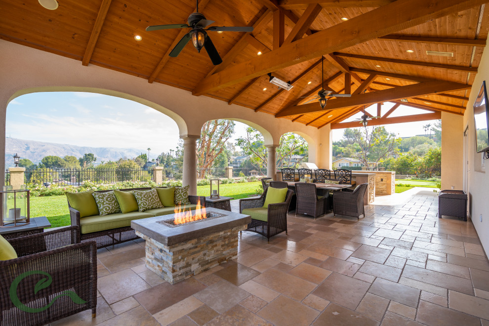 Großer, Überdachter Mediterraner Patio hinter dem Haus mit Outdoor-Küche und Natursteinplatten in Orange County