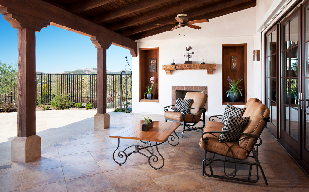 Photo of a large mediterranean back patio in San Diego with a roof extension and natural stone paving.