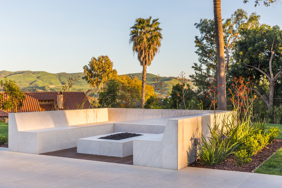 Design ideas for a contemporary back patio in Orange County with a fire feature, natural stone paving and no cover.