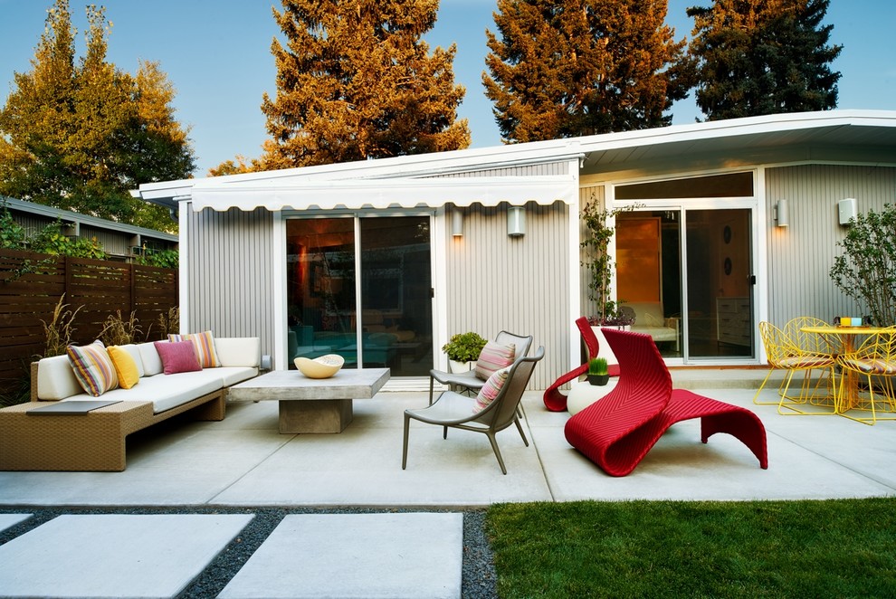 Example of a 1950s concrete patio design in Denver with an awning