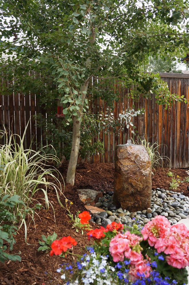 На фото: маленький садовый фонтан на заднем дворе в восточном стиле с покрытием из гравия для на участке и в саду