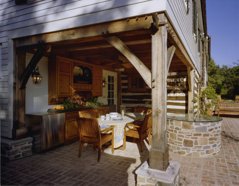 Foto di un patio o portico country dietro casa con pavimentazioni in mattoni e un tetto a sbalzo