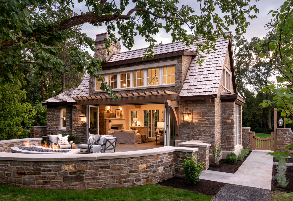 Cette image montre une grande terrasse arrière traditionnelle avec aucune couverture, un foyer extérieur et des pavés en pierre naturelle.