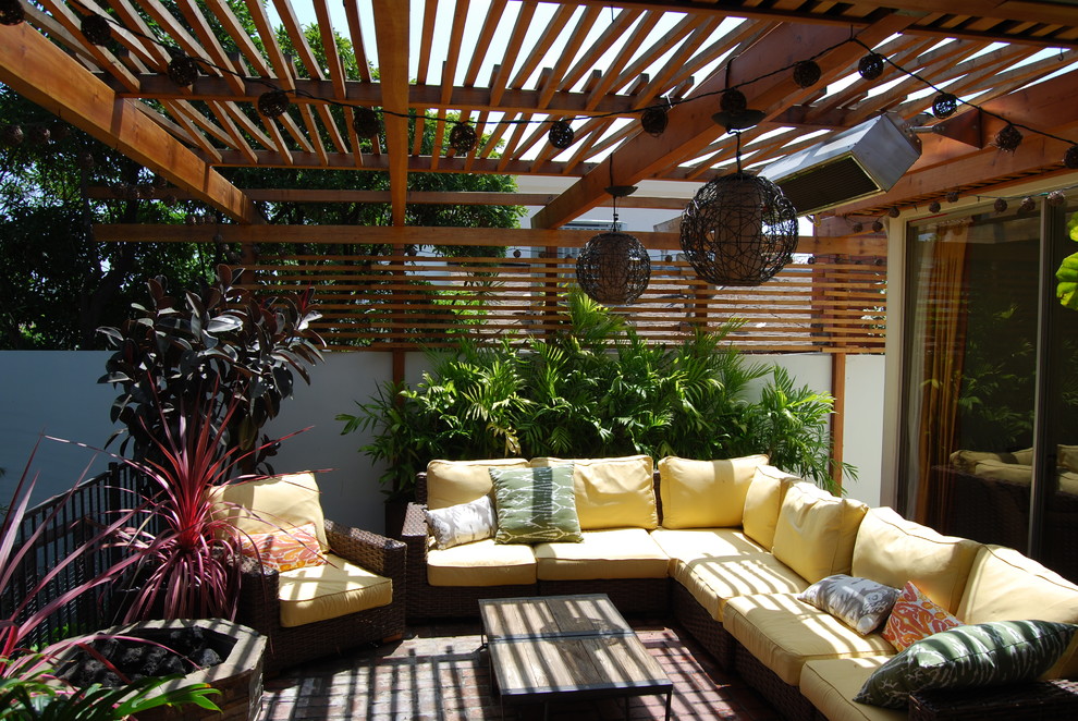 Cette photo montre une terrasse avec des plantes en pots latérale rétro avec des pavés en brique et une pergola.