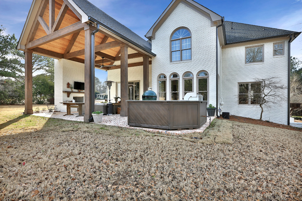 Foto di un grande patio o portico tradizionale dietro casa con un focolare, pavimentazioni in mattoni e un tetto a sbalzo