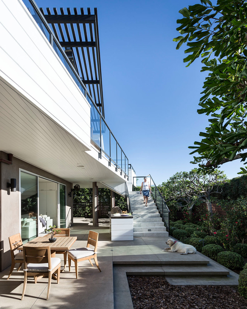 Aménagement d'une terrasse contemporaine avec une cuisine d'été, une dalle de béton et une extension de toiture.