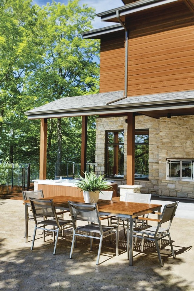 Idee per un patio o portico stile americano di medie dimensioni e dietro casa con lastre di cemento e un tetto a sbalzo