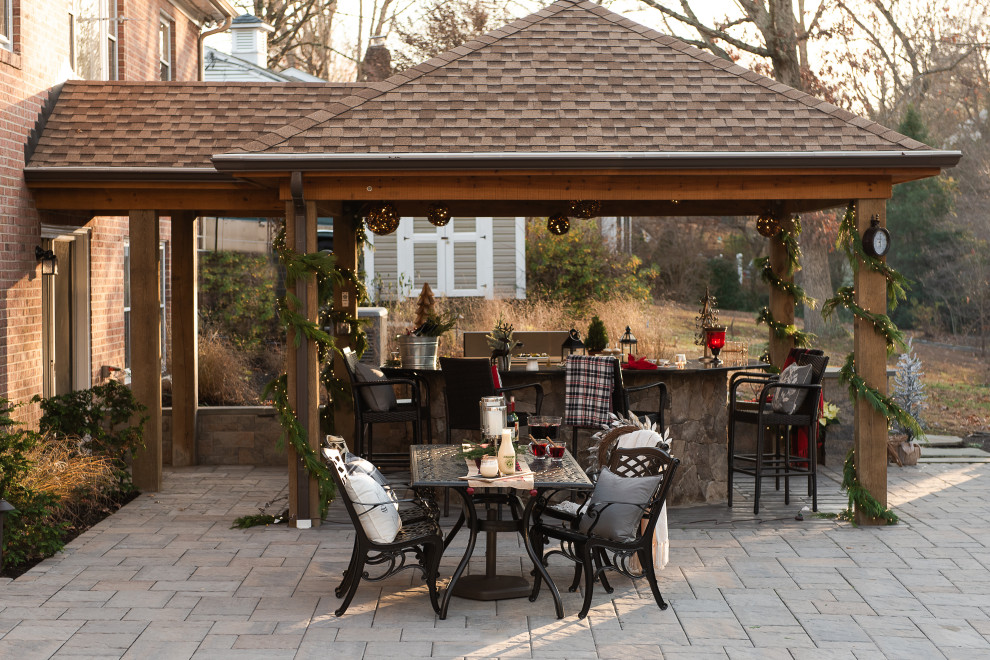 Modelo de patio clásico grande en patio trasero y anexo de casas con cocina exterior y adoquines de hormigón