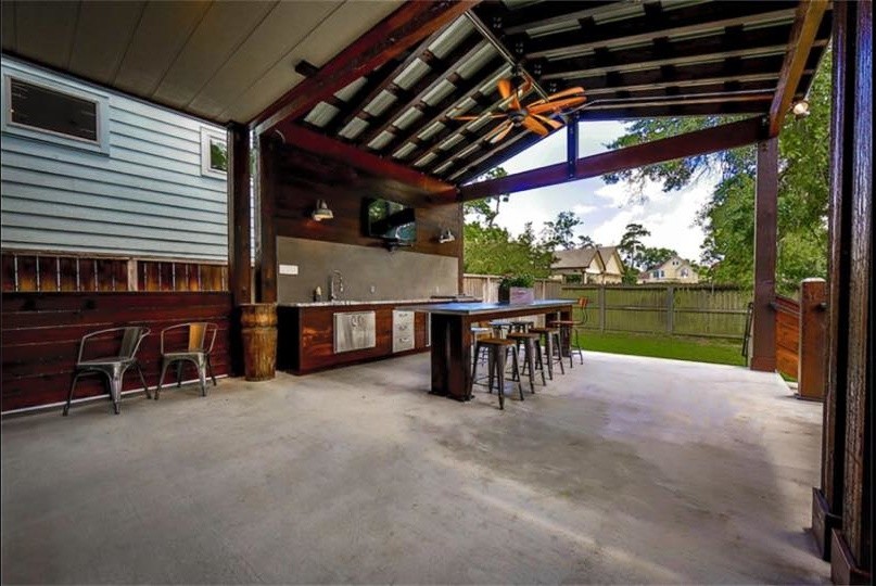 Cette photo montre une grande terrasse arrière industrielle avec une cuisine d'été, une dalle de béton et une extension de toiture.