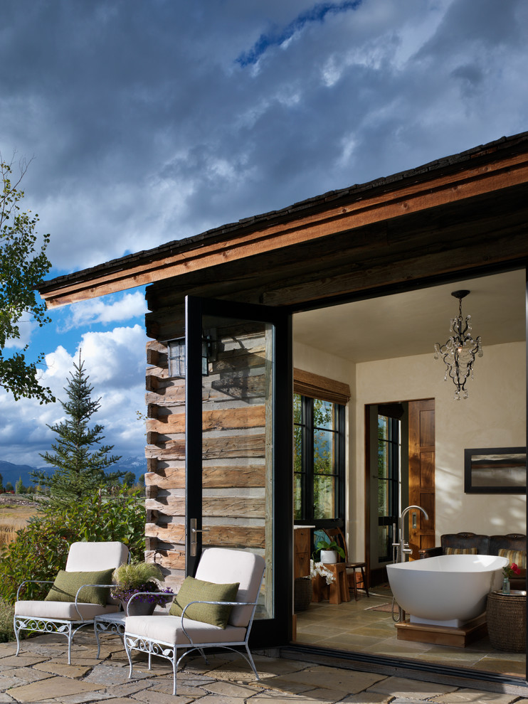 Exemple d'une terrasse arrière montagne de taille moyenne avec des pavés en pierre naturelle et une extension de toiture.