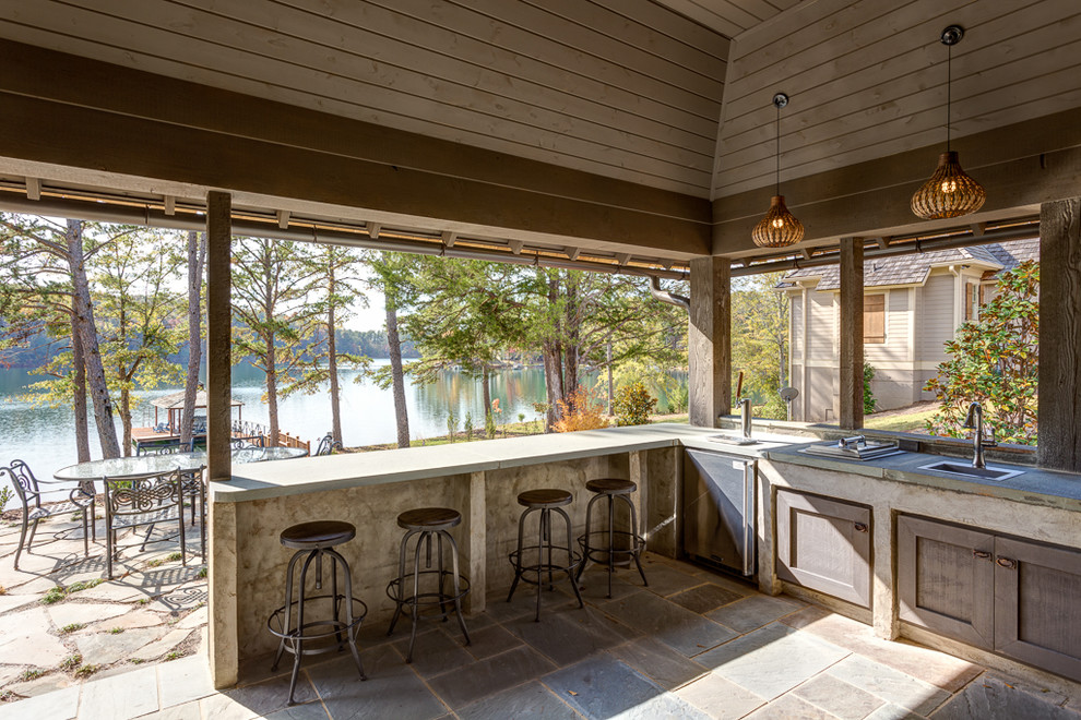 Cette photo montre une terrasse arrière bord de mer de taille moyenne avec une cuisine d'été, du carrelage et une extension de toiture.