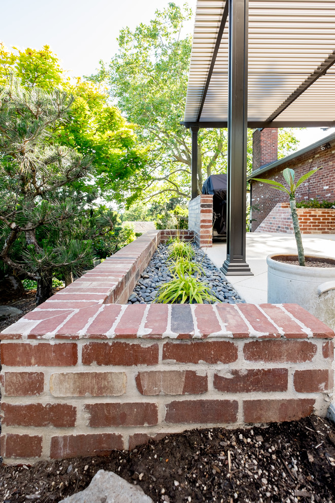 Modelo de patio clásico renovado grande en patio lateral con losas de hormigón y toldo