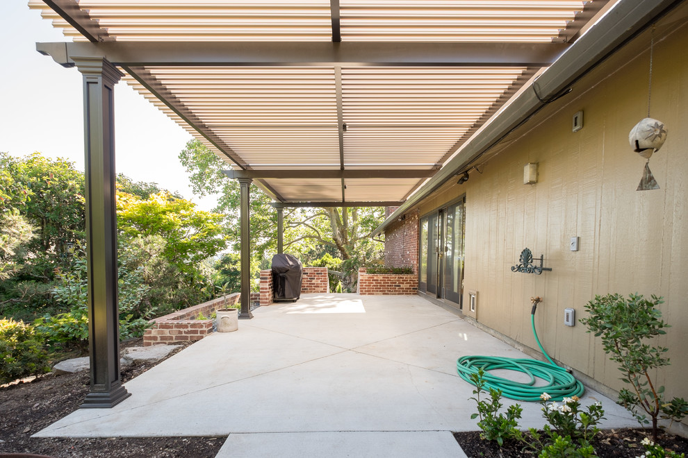 This is an example of a large classic side patio in Portland with concrete slabs and an awning.
