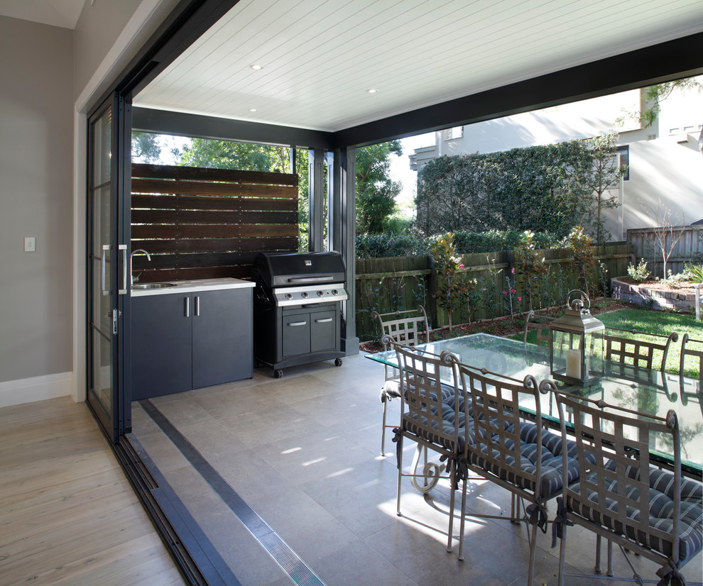 Cette image montre une terrasse arrière minimaliste avec des pavés en béton et une extension de toiture.